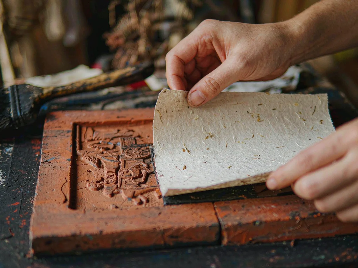 Hands pressing handmade paper onto an ancient carved Chinese brick